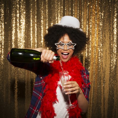 Young woman pouring champagne into champagne flute during party.